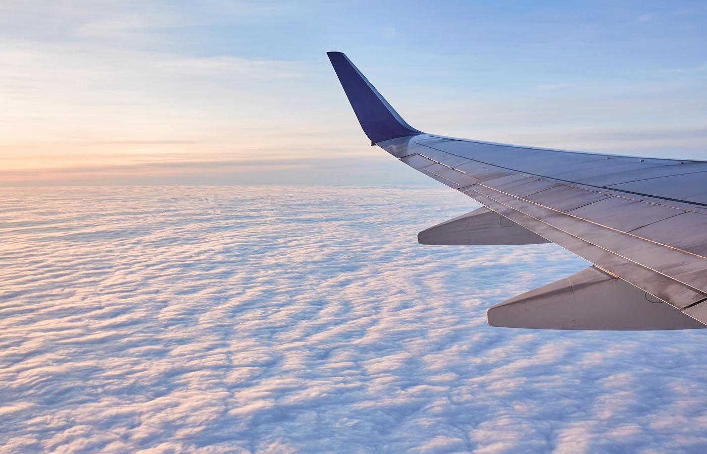 An aircraft wing above the clouds in early morning light