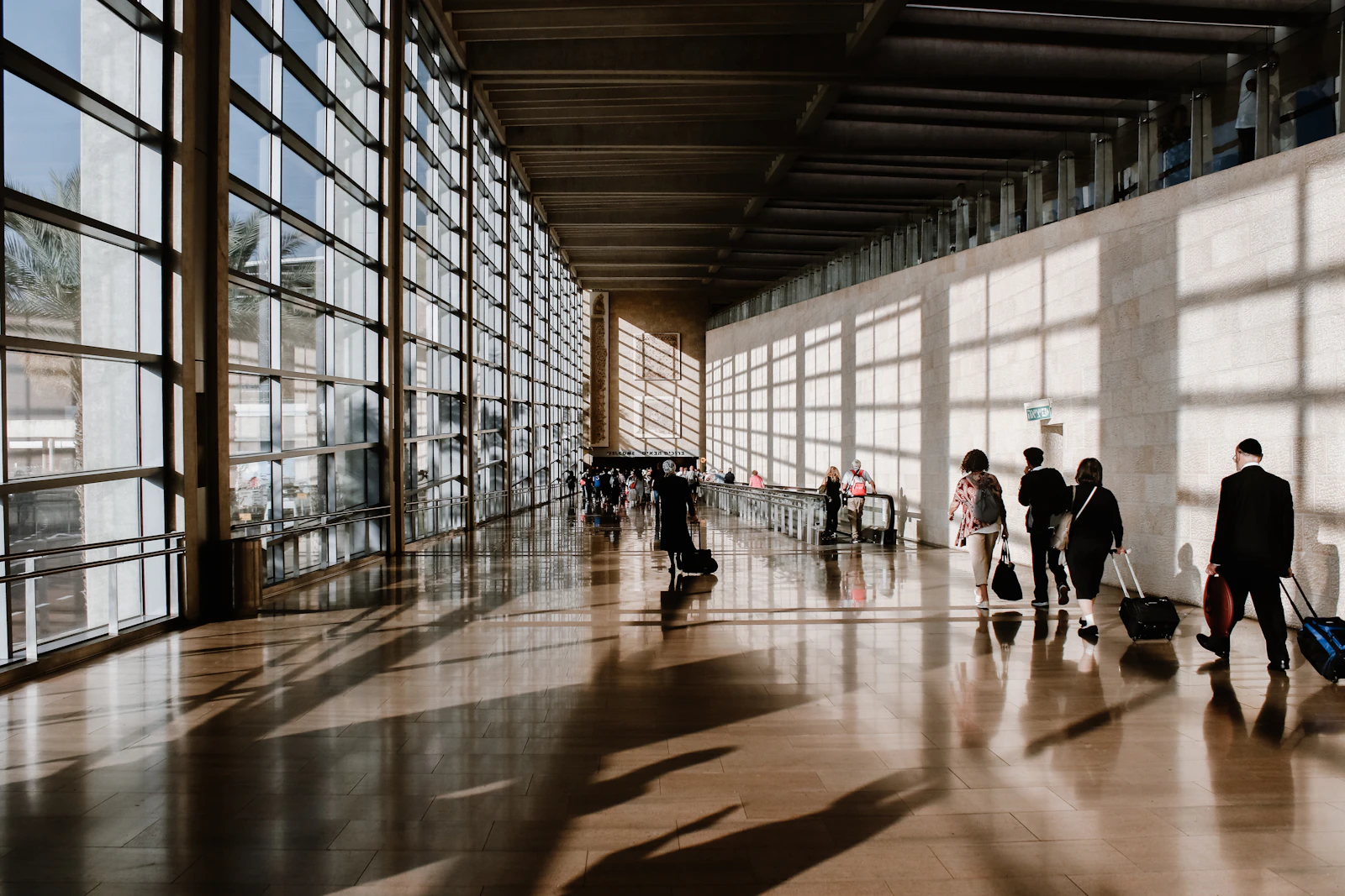 Business travellers walking with luggage through a bright airport terminal